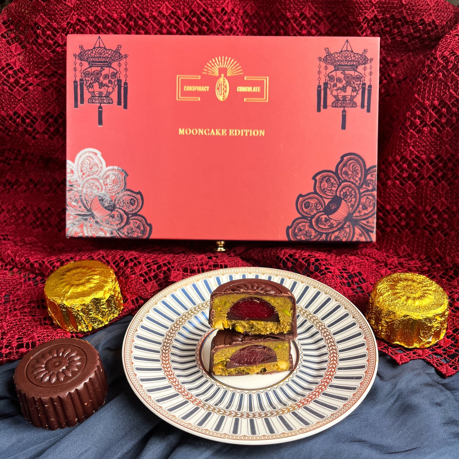 Red mooncake box with mooncakes on a decorative plate and red fabric background