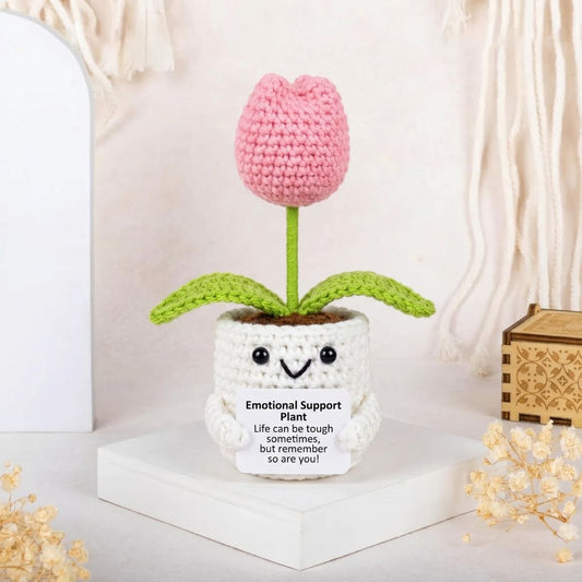 一株鉤織的粉紅色鬱金香，植株上綻放著一張笑臉，背景為白色。