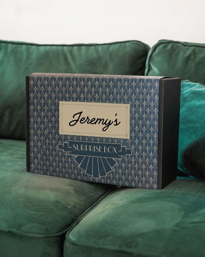 Personalized surprise box labeled 'Jeremy's Surprise Box' on a green couch.