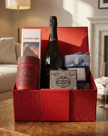 Gift basket with wine, snacks, and games on a table in a living room.