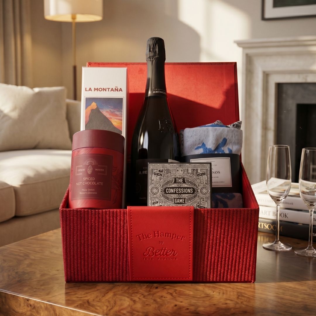 Gift basket with wine, snacks, and games on a table in a living room.